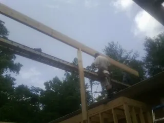 Carpenter setting a ridge beam over a new addition frame — Ice Dam Removal by Roofing Brothers in Swansboro