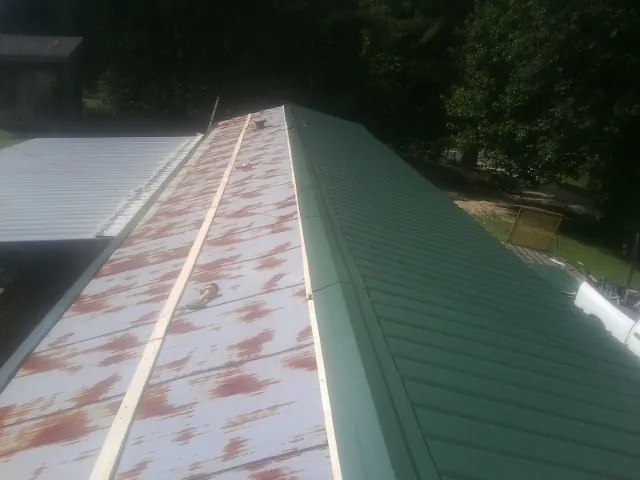 Old rusted panels beside newly installed green metal roofing — Wind Damage Roof Repair by Roofing Brothers in Swansboro