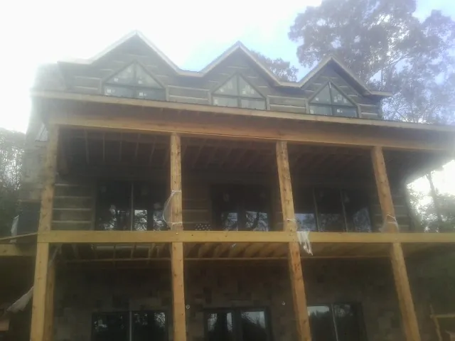 Dormers and porch framing on a large log home under construction — Roof Coating work by our crew in Swansboro