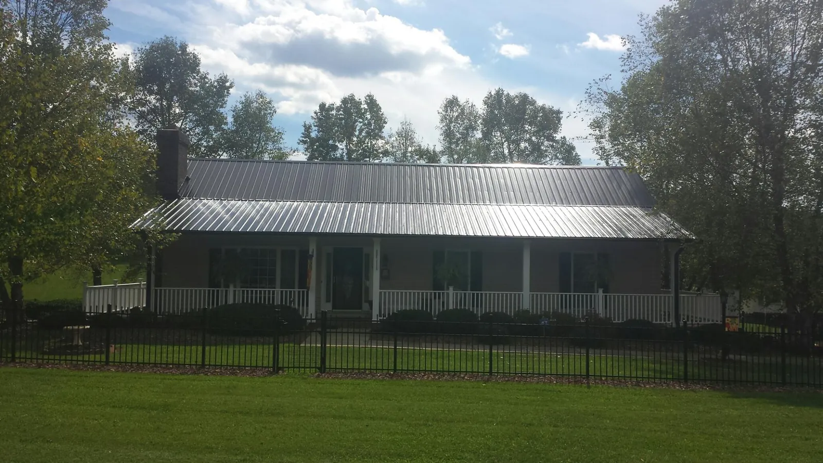 Gray metal roof on a brick ranch with a full width front porch — Gutter Guard Installation work by our crew in Swansboro
