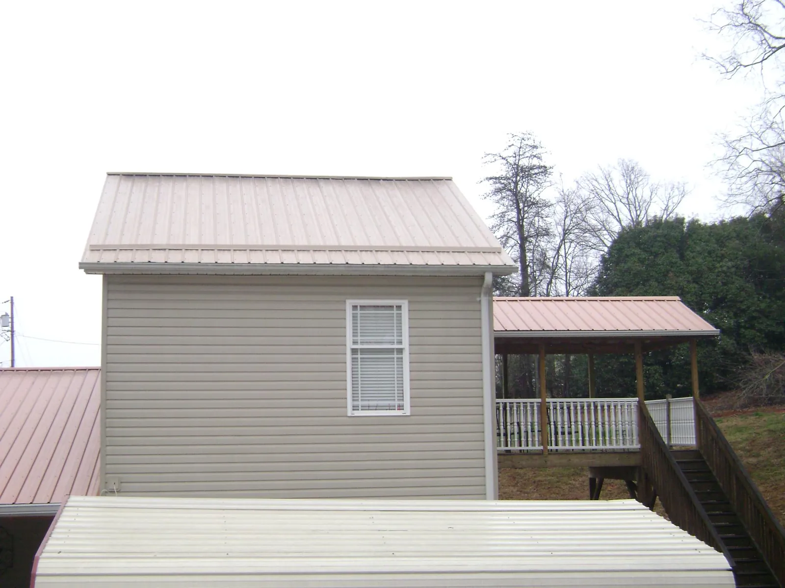 Tan metal roofs on a two story addition and attached porch, from a Roof Replacement job in Swansboro