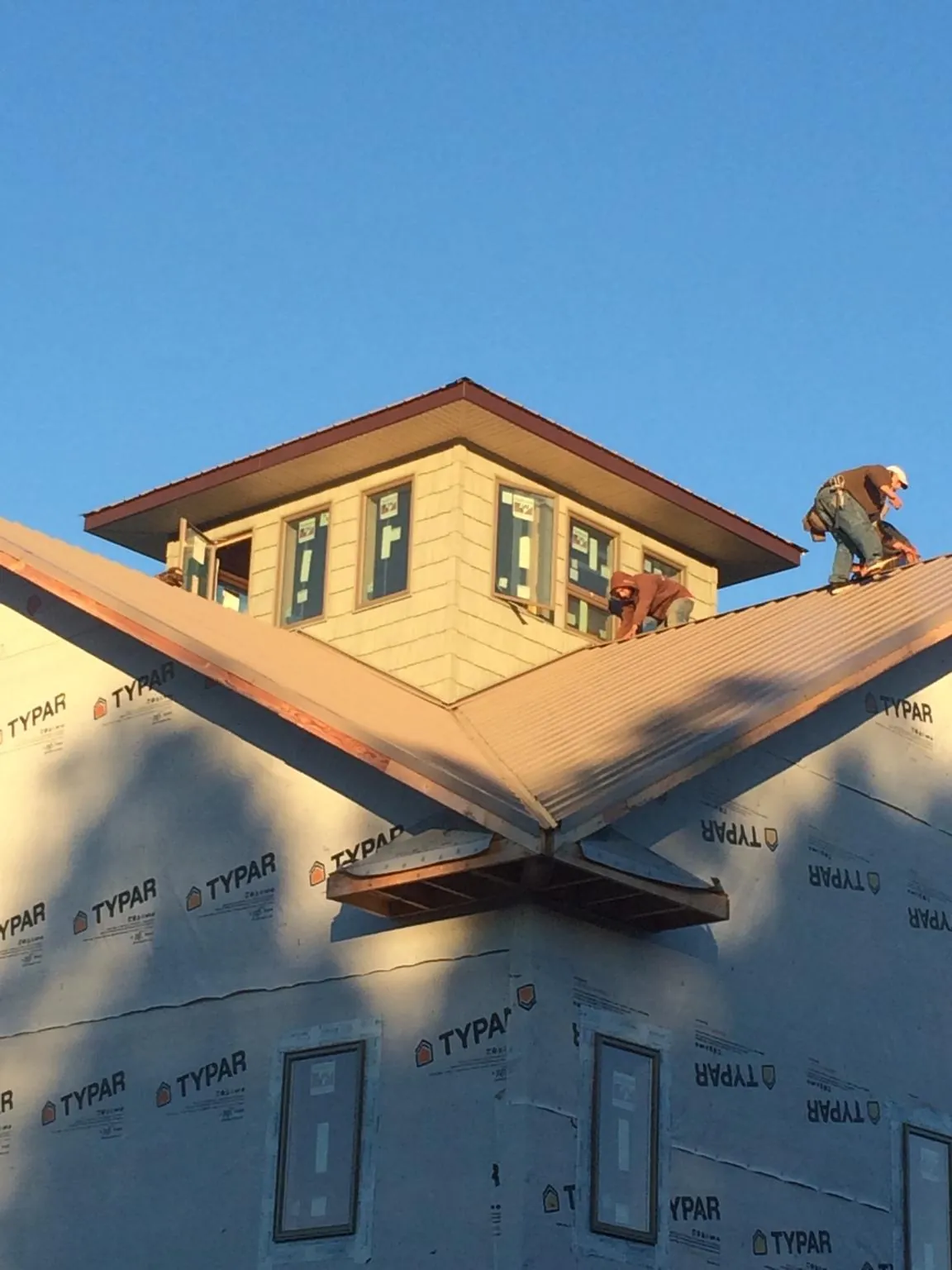 Roofers working around a rooftop cupola on a new metal roof at sunset — Roof Waterproofing in Swansboro by Roofing Brothers
